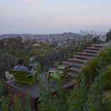 Previously “leftover” space, a secluded deck featuring two green Loll chairs offers stunning views of downtown.  Photo 5 of 8 in Outdoor by Bradford Schmidt from A Spa-Like Patio with Stunning Views Cascades Down a Los Angeles Hillside