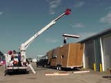 Woody camper trailer frame and building materials being dropped onto flatbed trailer