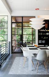 Dining Room, Table, Chair, Pendant Lighting, Rug Floor, and Shelves In the dining area are a Gamma table by Cappellini, Eames molded plastic chairs, and a Flotation pendant by Ingo Maurer.  Photo 7 of 11 in A Couple Takes an Unassuming Plot of Land and Calls it Home
