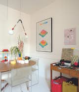 A series of bright colors and geometrical shapes fill the kitchen of Tauba Auerbach's Brooklyn home. A 2008 light sculpture by Andy Coolquitt hangs above the table with a range of objects lying atop, including candles by Andrej Urem, salt and pepper mills by Muuto, and a Memphis-inspired table lamp. The colorful work on paper is by Kamau Amu Patton. The red and yellow tote bags are by fiber artist Doug Johnston.