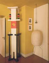 A sculptural "totem" by Ettore Sottsass presides over a corner of a dining area, near two Jasper Johns prints and a Noguchi-like lantern, in the home of painter Francesco Clemente.