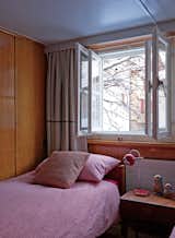 One of the daughters’ rooms has a Danish rosewood bed and side table from Modernistiks. Tuckey found the 1970s red enamel-and-chrome lamp at Golborne Road market in London. Double windows help keep the Alpine winter chill at bay.  Photo 4 of 12 in A Sliced-Up House Comes Together Again