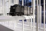 Model trains travel through the store, weaving in and out of the rods.  Search “best snow” from Snarkitecture Takes on Holiday Windows with Minimal Snowscape