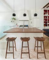 In the mostly-white kitchen, black Topan pendants by Verner Panton pop. The butcher block counters are an unusual height, so Lee designed custom-made stools to fit.