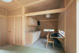 It also includes a small kitchenette equipped with a sink, wooden countertop, and a dining area/nook. The door to the left leads to a bathroom.