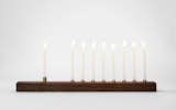 Celebrate Hanukkah this year with the elegant walnut menorah from Marmol Radziner. The menorah is handcrafted from solid walnut wood and bronze, giving it a one-of-a-kind quality that is met with a rich, warm look. With illuminated candles, the wood and bronze gives off a soft reflective glow, which is aided by the mineral oil finish to the walnut wood.