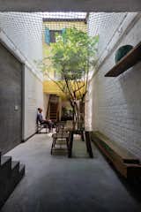 The family enjoys a shared meal in the ground floor alleyway, which serves as a gathering place, dining area, and playground. Native trees are planted on the ground floor as well as on balconies and in the steel frames, covering the home with plants and shifting the natural world inside.