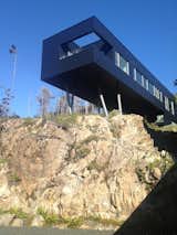 The L-shaped secondary building perches over a craggy escarpment. It offers the best vantage point for taking in the moss-planted roof, forest, and ocean.