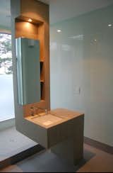 In this bathroom, a twisting concrete volume rises out of the floor to form the sink, vanity, medicine cabinet, as well as a wall for the showerhead behind.