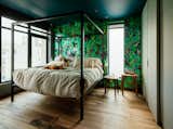Zames decided on Farrow & Ball's Hague Blue color for the bedroom ceiling to make the space feel more intimate, but juxtaposed it with another wallpaper from Flavor Paper. The bed is from Room & Board and the Fawn tables are by Rich Brilliant Willing.