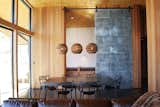 Two more patinated panels conceal “the nest”—a nook containing two standard mattresses that double as a couch. Three Graypants Scraplights hang above a Parsons dining table from Room & Board and Masters chairs by Philippe Starck.