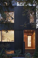 “The house is a three-story volume, but in order to minimize the reading of this volume from the street, we set the walls of the third floor back from the front and rear walls of the building,” Clarkson said. Black wood v-joint siding foils Douglas fir wood cladding around the door.