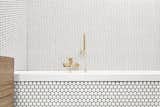 The entire room is surfaced in white mosaics from Hisbalit; the bath fixtures are brass and sourced from a local Czech retailer.