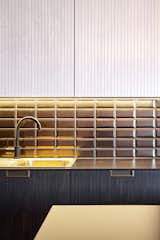 Golden brown subway tiles from Diffusion Ceramique face a black countertop from Fundermax.