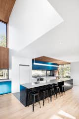 Since one of the homeowners is passionate about food and cooking, Rasselet made an oversized kitchen the focal point of the home. Hudson iron counter stools from Structube sit beneath a suspended MicroSquare LED fixture from Philips Ledalite.  Photo 2 of 4 in House of the Week: Splash of Color in an Otherwise Minimalist Home by Luke Hopping