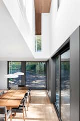 “Conceptually, all of the spaces in the house are connected to the kitchen and dining area by the stairwell, the second-floor catwalk, or through the glass in the living room,” said Rasselet. The dining room’s walnut table and chairs are by Atelier LC2, and the Cliff light fixture is by Lambert & Fils.