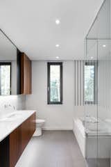 DuPont Zodiaq Quartz countertops in Snow White and a Duravit Starck 3 sink stand across from a tub by Acryline Inc. in the bathroom. Between them, Arctic White and Suede Gray squares from Daltile lead to an American Standard toilet.