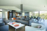 The ground floor features the master bedroom suite, living room, dining area and kitchen in addition to a huge wrap-around balcony. To accommodate so many floor-to-ceiling retractable glass doors, Schultz had to get creative with structural elements, as seen here with three black steel poles supporting the cathedral ceiling. The living area features a B&B Italia sofa.
