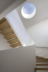 A small circular skylight serves as a vertical focal point in the center of this stairwell, and provides much-needed natural light. The white walls of the stairs bounce light, but the darker wood treatment ensures that the space is not too bright.