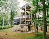 Connected to the main house by a narrow bridge, a three-story cedar tower with a sauna at its base recalls a tree house. The screened-in second level includes a table and chairs for enjoying an outdoor meal, while a swing on the tower’s top level provides a perch to take in the surrounding birch trees.