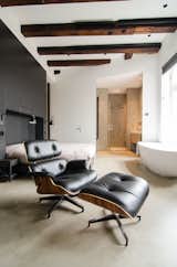 When planning the renovation, the owner gave Standard Studio complete freedom to develop the design. In the unconventional bedroom, the bed sits against a black feature wall, with a prominent freestanding bathtub on the opposite side. In addition to the wood beams, all original windows from the old sugar refinery were preserved, to keep the "soul" of the building intact.