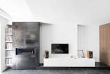 The communication between interior and exterior is unmistakable. The polished steel that surrounds the fireplace and the concrete floor’s dark finish recall the home’s exterior, while the contrasting stark white walls create a visual language as striking as the building’s black facade.