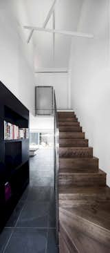 The staircase’s steel guardrail and the custom black bookshelf create a link between the kitchen, the living space, and the entryway.