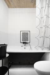 The approximately 4 inch by 4 inch white ceramic tile flooring is typical of Soviet-era bathrooms. Vorontsov sought to update the utilitarian style of the original bathroom with Kludi Bozz fixtures (which he painted black himself) and a graphic IKEA shower curtain.