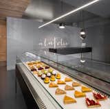 The refrigerated, black steel display cases were custom designed and fabricated. The compressors for each unit are located in the basement, allowing the cases to stand on delicate legs and preserving the minimalist look of the space.  Search “www.x42.shop” from A Modern Patisserie in Montreal