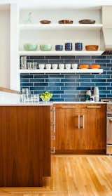 The residents have a particularly strong sense of color and love to cook with their son, so no-fuss finishes likes these blue tiles from Heath Ceramics were an ideal choice. The tiles combine with colorful tableware and custom walnut cabinetry to make a vibrant inteiror.