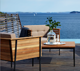 From Danish company Skargaarden, the Häringe Lounge Armchair is crafted in teak and features a black powder-coated steel frame and natural grey cushions. Covered in a durable sunbrella fabric, the cushions are designed for use outdoors, making the armchair an excellent choice for a patio or deck. The chair can be oiled once a year to retain the rich teak color, or left alone to develop a silvery grey patina over time.