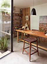 Office, Craft Room Room Type, Desk, and Concrete Floor In her workshop, which features a Mercedes table, an Otto lamp, and a wood-and-leather bar stool, all by NET, she creates a line of uncomplicated wood toys called Sarmiento.  Photos from One-of-a-Kind Furniture Fills This Delightfully Serene Buenos Aires Home