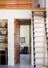 A custom steel and red oak ship ladder in the main living area is another space-saving solution. The door is Douglas fir and the shelving is mesquite wood; an Eames lounge chair can be seen in the master bedroom.
