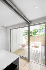 An aluminum-framed door leading to the terrace provides an added sense of depth, integrating outside with inside. Here, the metal contrasts sharply with the natural birch flooring.
