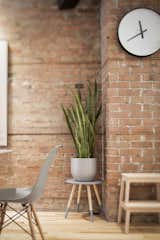 A succulent sits atop a stool from Zone Maison, juxtaposed against a warm brick wall.