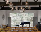 Located in the renovated barn, the living room can be transformed into a performance space that seats 80. The art piece is from South Africa. Accompanying the Steinway piano is a sideboard from Restoration Hardware; the pendants are from Cisco Home.