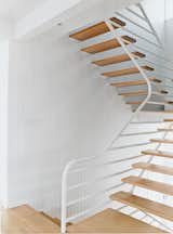 The main staircase consists of simple oak treads that cantilever out from side walls sheathed in natural vertical board and are supported on the other side by a continuous grill-like railing truss.