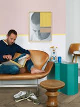 Aumas reads on a vintage Swan sofa by Arne Jacobsen. The teal side table is from a Berlin flea market; the walnut stool by Charles and Ray Eames is from an antique store in Brussels; Aumas himself made the art on the wall.