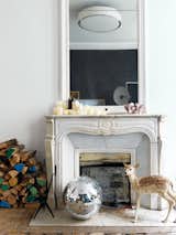 Aumas created a series of vignettes throughout the apartment that are playful and unexpected, mixing fun elements with practical and historic details. Here, an original marble fireplace is paired with a disco ball, a stuffed fawn, and firewood that's selectively been painted in bright colors.