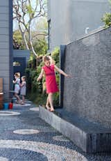 Outdoor, Back Yard, Front Yard, and Side Yard The water wall was one of the family’s main requests. Not only does it provide the girls— Serafina, Carolina, and Madeleine—a place to play, it also blocks street noise.  Photo 5 of 6 in A Heavenly Backyard is Precise with Pebbles