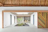 Architect José Roberto Paredes calls the sliding walls utilitarian artwork. “The doors open to a surprise space, like a secret pathway,” he says.  Photo 4 of 6 in Bursts of Yellow and Indoor Gardens Are Just Two Reasons to Love This Home