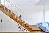 Staircase, Wood, and Metal Each inch is accounted for in the 1,916-square-foot home. Cabinets and clever storage for wine are tucked under the stairs.  Staircase Photos from It Looks Like a Playland but This Home Works Hard