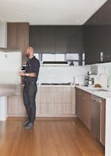 Malboeuf stands at a Fisher &amp; Paykel refrigerator in the kitchen. He and Bowie shopped around to find appliances that balance cost and performance: the dishwasher is Bosch, the gas cooktop is Dacor, and the oven is Fagor. Walnut veneer clads the cabinets, and the floors are bamboo.  Photo 8 of 11 in 18th Ave City Homes by Joe Malboeuf from Three Families Comfortably Fit in One Slim Lot