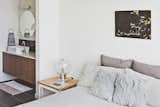 Bowie designed the nightstand, which acts as a prime perch for a vintage lamp her parents purchased in the Netherlands. The wall paint throughout the unit is Eider White by Sherwin-Williams.  Photo 6 of 12 in Three Families Comfortably Fit in One Slim Lot