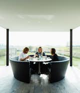 Dining Room, Table, Recessed Lighting, Dark Hardwood Floor, and Bench Wynants lives in the house with his wife, Hilde Louwagie, and their three children. His own circular seating design, Kosmos, is in the kitchen.  Photos from A Kubrick-Esque Farmhouse Kicks Its Fossil Fuel Habit