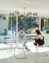Large sliding glass doors were added to the dining room, which is outfitted with an Eero Saarinen table, Tobias chairs from IKEA, and a chandelier by Lindsey Adelman.  Photo 6 of 11 in Jenni Konner’s Hollywood Pad Is Ready for Its Close-Up