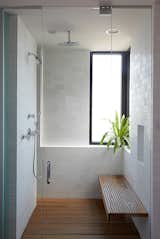 A clean and simple shower in Chicago is lined with modern subway tiles and a wood shower bench.