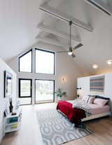 Passive House bedroom with ceiling fan and exposed ceiling beams painted white.