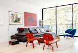 The main floor is arranged as one long, contiguous space, with a living area and balcony at the front end. An Aulia coffee table by Henk Vos, a pair of red Eames molded plywood chairs, and a Pelican chair by Finn Juhl center the space.