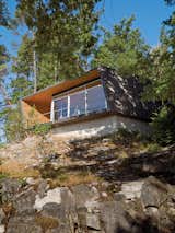 Outdoor, Slope, Trees, Boulders, and Shrubs Perched over a cliff face, the hooded deck of the Gambier Residence reads like a ship’s prow over Howe Sound, the scenic waters near Vancouver.  Outdoor Boulders Trees Photos from When Living on the Edge is Super Comfortable